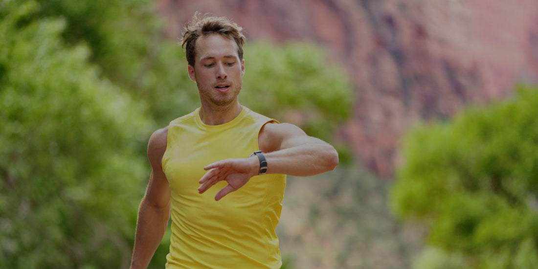 Man in yellow sleeveless shirt checking his watch with a natural landscape in the background