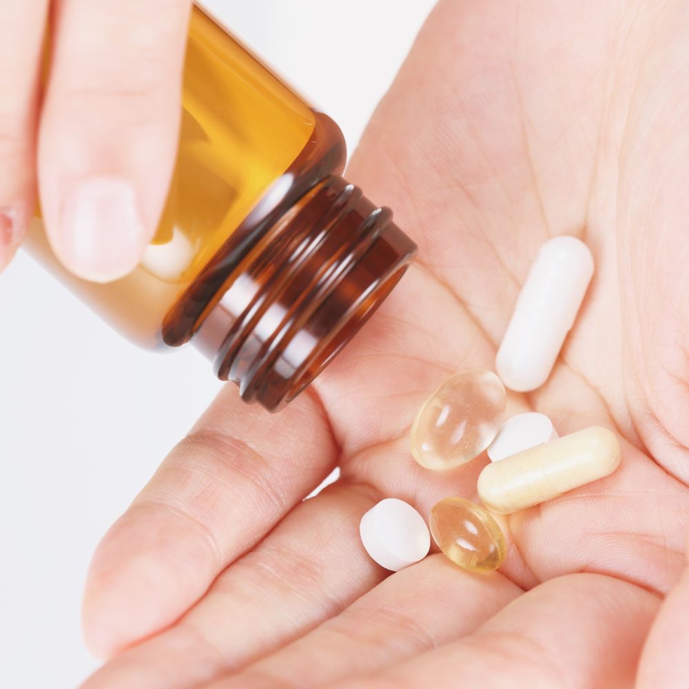 Hand holding a small bottle of pills with a close-up view on a white background